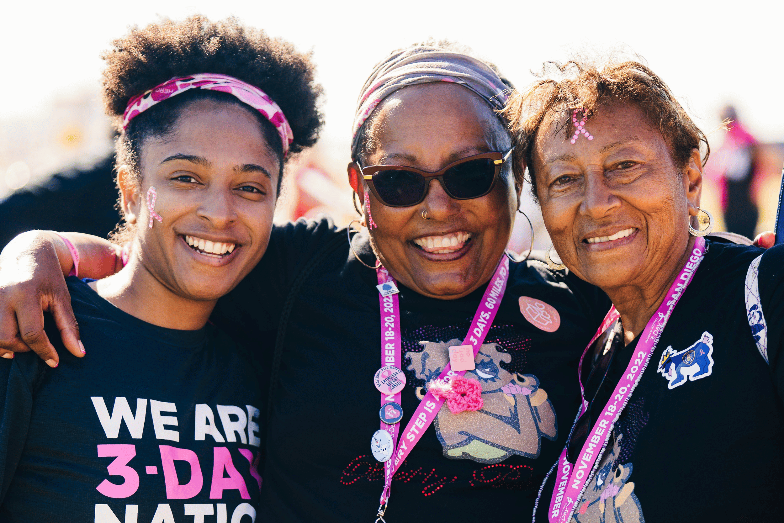 three smiling women with lanyards and t-shirts from a fundraising event